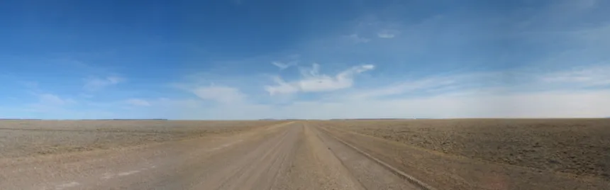 Un tramo recto de la Ruta 40 atraviesa un paisaje árido bajo un cielo despejado.