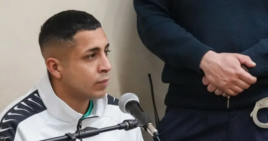 Un hombre sentado ante un micrófono en una sala judicial.