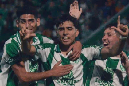 Tres jugadores de verde y blanco festejan un gol en la cancha.