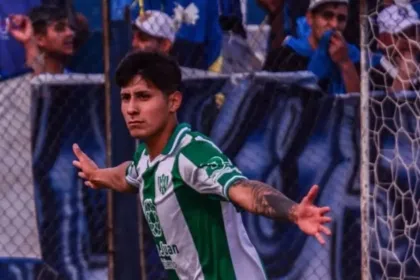 Un futbolista de verde y blanco celebra frente al arco, con hinchas detrás.