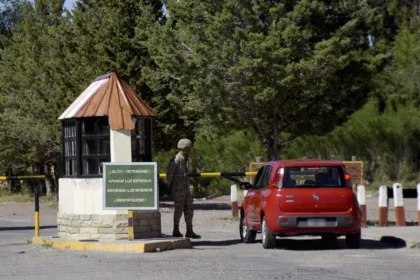 Acceso del cuartel del Ejército en Zapala, con una garita, un soldado de guardia y un auto rojo en la barrera.
