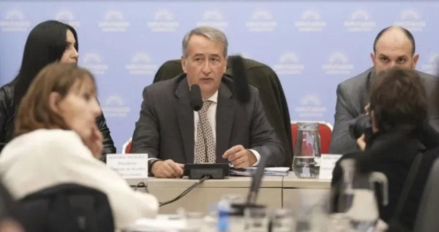 Un hombre habla durante una reunión de comisión en una sala con otras personas.