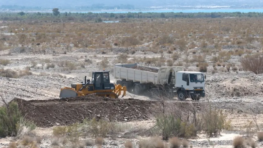 Una topadora y un camión trabajan en el cauce seco del río.