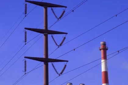 Torre de alta tensión y cables eléctricos contra un cielo azul
