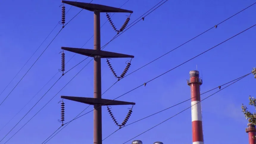 Torre de alta tensión y cables eléctricos contra un cielo azul