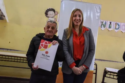 Un hombre sostiene un documento del Gobierno de San Juan junto a una funcionaria.