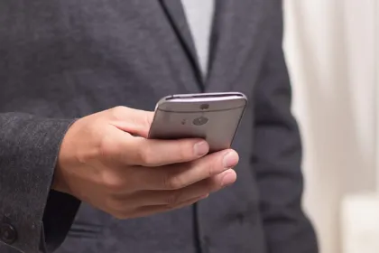Una persona sostiene un teléfono móvil con la pantalla hacia abajo.