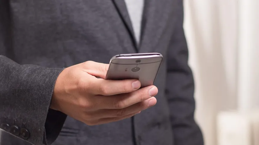 Una persona sostiene un teléfono móvil con la pantalla hacia abajo.