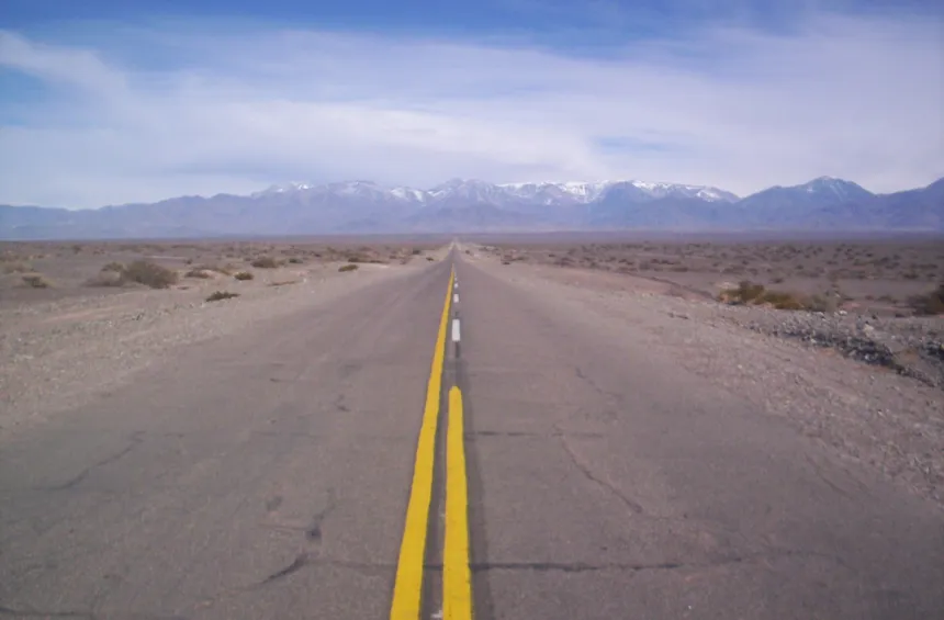 La Ruta Nacional 150 se extiende hacia montañas con nieve en las cumbres.