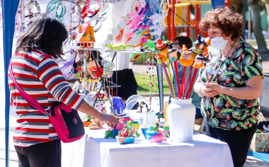 Dos mujeres en un puesto de artesanías durante una feria al aire libre.