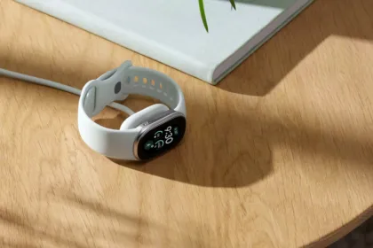 Pulsera de actividad blanca con pantalla sobre una mesa de madera.