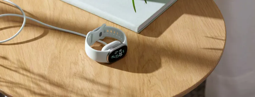 Pulsera de actividad blanca con pantalla sobre una mesa de madera.