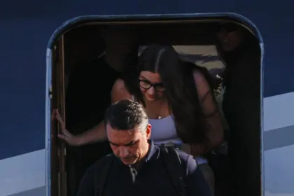 Flávio Bolsonaro baja de un avión, seguido por una mujer.