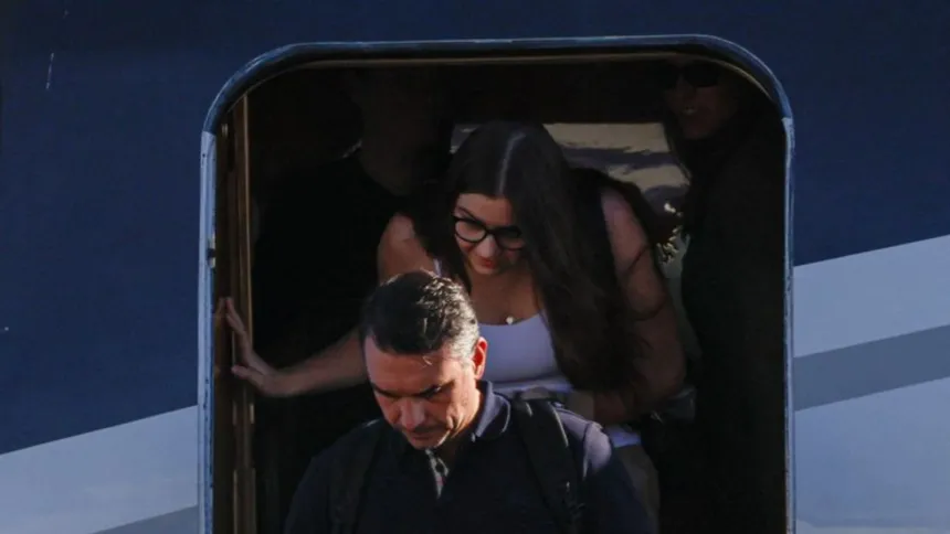Flávio Bolsonaro baja de un avión, seguido por una mujer.