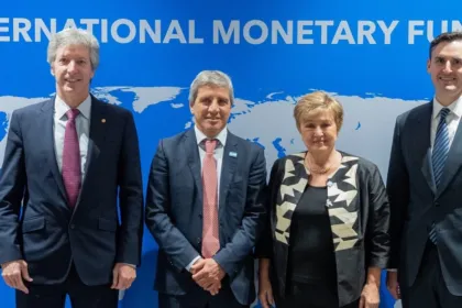 Cuatro funcionarios posan frente al fondo del Fondo Monetario Internacional.