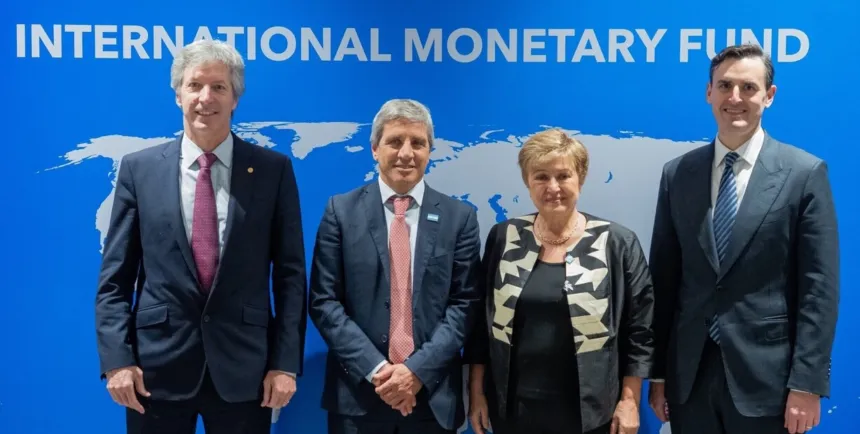 Cuatro funcionarios posan frente al fondo del Fondo Monetario Internacional.