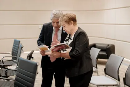 Dos adultos revisan un documento en una sala de reuniones.