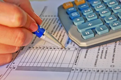 Una persona completa un formulario impositivo junto a una calculadora.