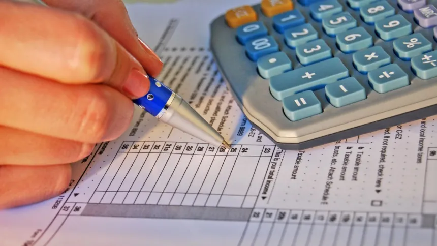 Una persona completa un formulario impositivo junto a una calculadora.