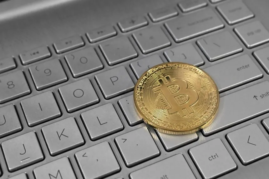 Moneda con el símbolo de Bitcoin sobre el teclado de una computadora portátil.