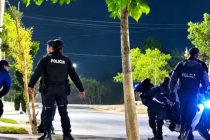 Policías junto a una motocicleta en una calle iluminada de noche.