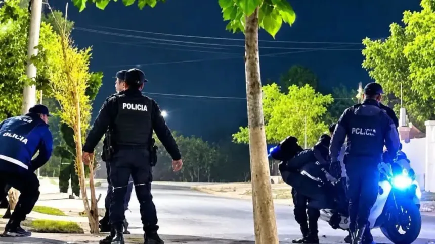 Policías junto a una motocicleta en una calle iluminada de noche.