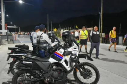 Policías en motocicletas junto a participantes y asistentes en una zona peatonal
