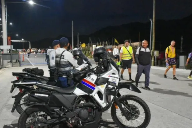 Policías en motocicletas junto a participantes y asistentes en una zona peatonal
