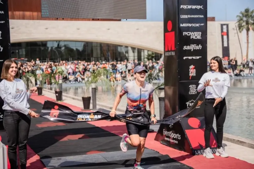 Una atleta cruza la meta de una competencia IRONMAN ante el público.