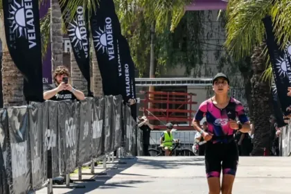 Una triatleta corre por el circuito de la competencia entre vallas y espectadores.