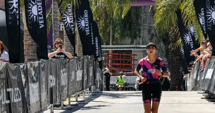 Una triatleta corre por el circuito de la competencia entre vallas y espectadores.