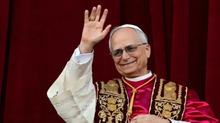 El papa León XIV saluda con la mano frente a una cortina roja.