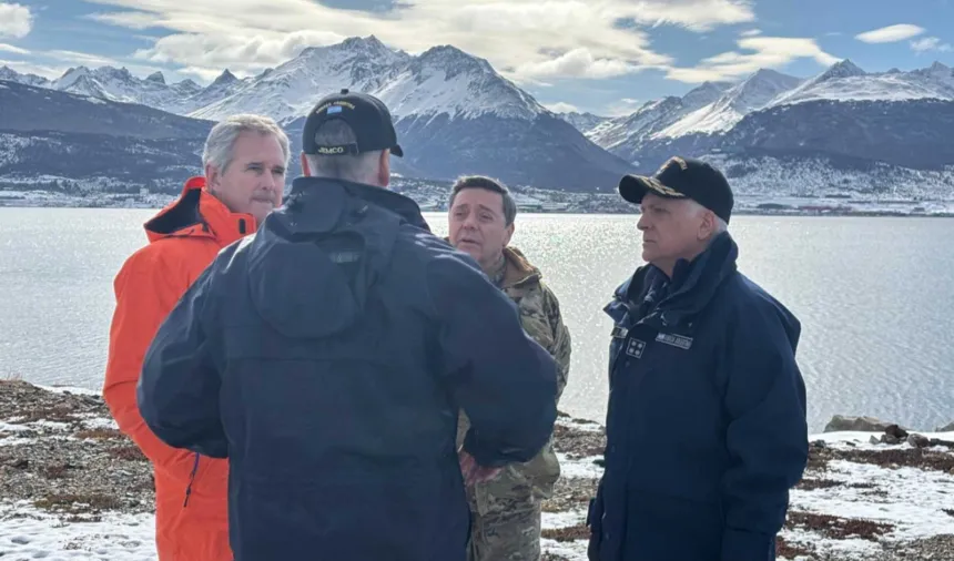 Cuatro hombres conversan frente a una costa nevada y montañas en Ushuaia.