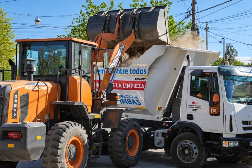 Una pala cargadora descarga residuos en un camión de limpieza de la Municipalidad de Chimbas.