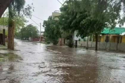 Una calle inundada por la lluvia, con agua frente a varias viviendas.