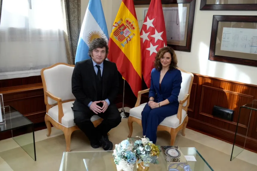Milei e Isabel Díaz Ayuso sentados en una oficina, con tres banderas detrás.