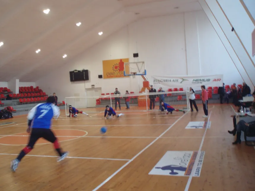 Un partido de goalball se juega en una cancha cubierta.