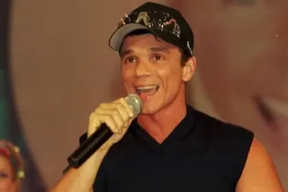 Un cantante con gorra canta sosteniendo un micrófono.