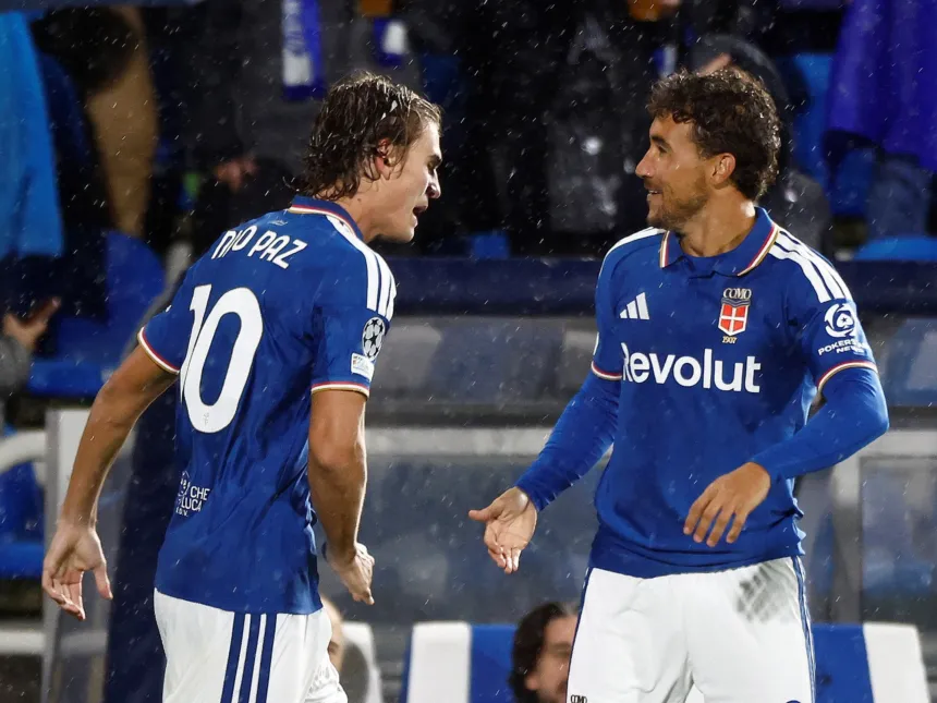 Nico Paz y un compañero del Como se saludan durante un partido bajo la lluvia.