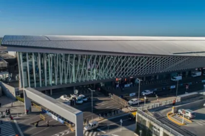 Vista aérea de una terminal aeroportuaria con vehículos y pasajeros en el acceso.