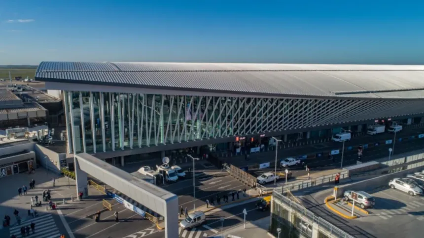 Vista aérea de una terminal aeroportuaria con vehículos y pasajeros en el acceso.
