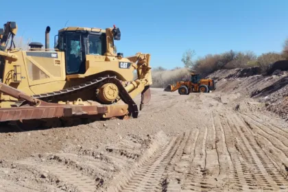 Dos máquinas realizan trabajos de encauzamiento en un cauce seco.