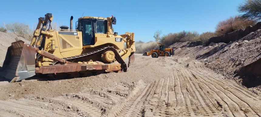 Dos máquinas realizan trabajos de encauzamiento en un cauce seco.