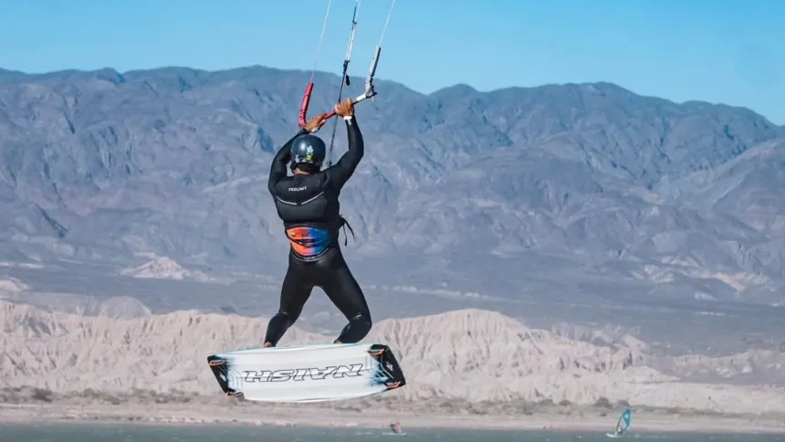 Una persona practica kitesurf frente a montañas en un paisaje de San Juan.