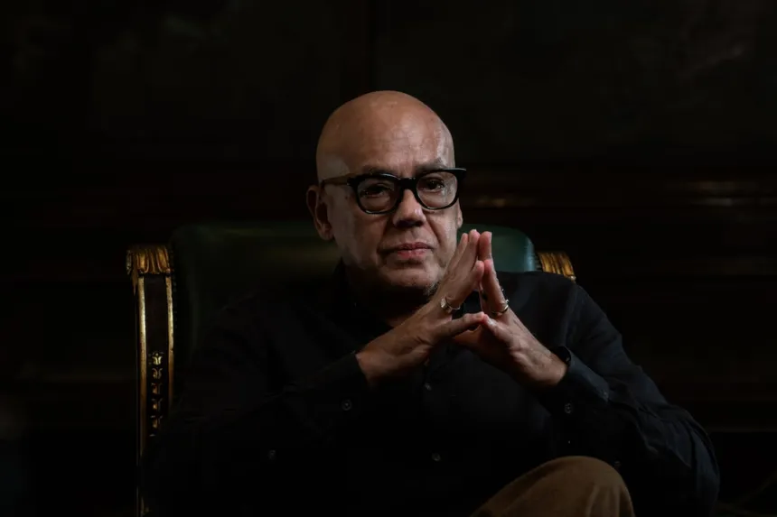 Jorge Rodríguez sentado en un sillón, con anteojos y las manos juntas.