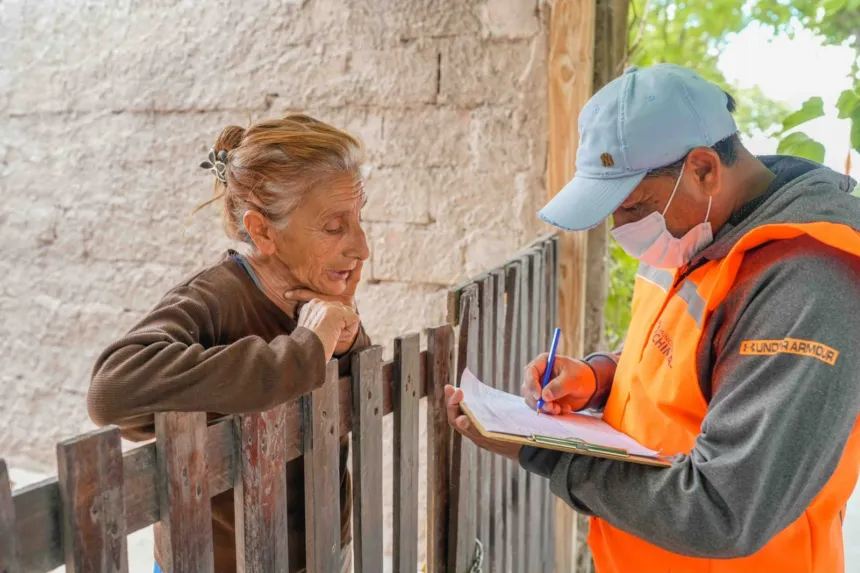 Un trabajador municipal conversa con una vecina y anota información en una planilla.