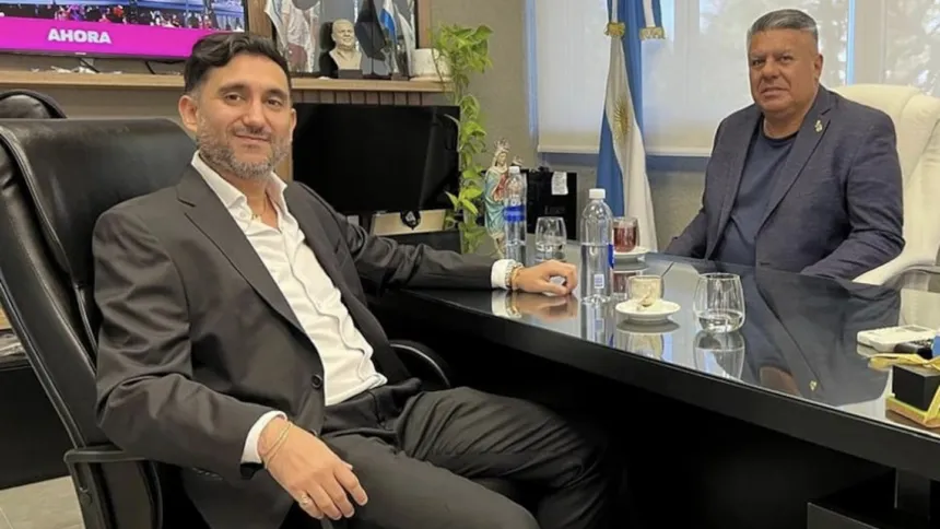 Dos hombres conversan sentados frente a frente en una oficina.