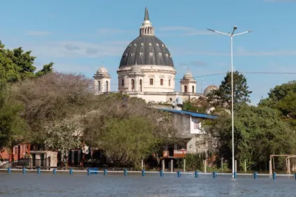 Agua cubre una calle frente a viviendas y un edificio con cúpula.