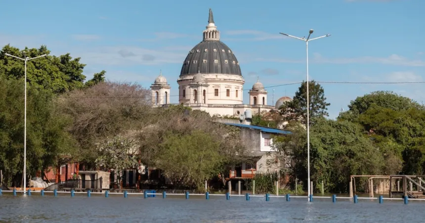 Agua cubre una calle frente a viviendas y un edificio con cúpula.