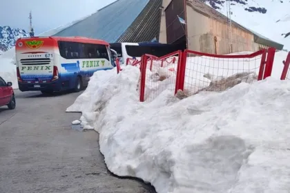 Un autobús y un automóvil junto a un edificio de control y nieve acumulada